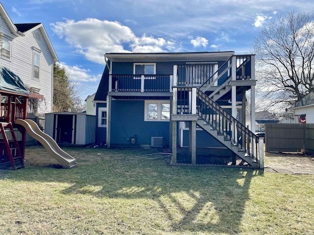 back of property featuring a yard, a balcony, a playground, and a storage unit