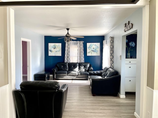 living room with a textured ceiling, light hardwood / wood-style flooring, and ceiling fan