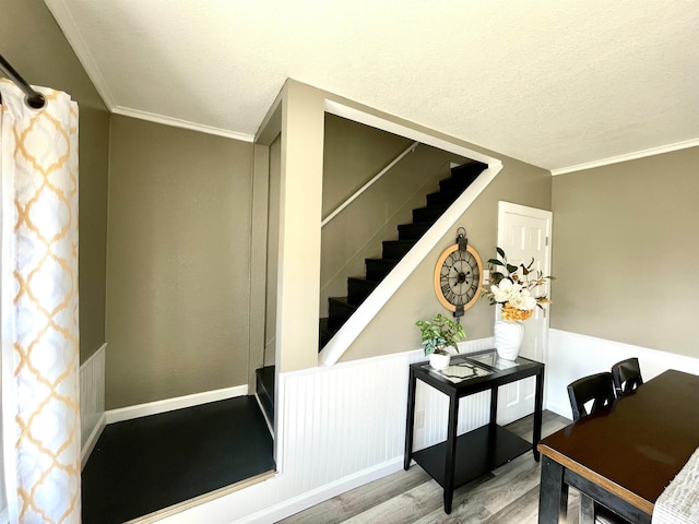 stairway featuring hardwood / wood-style flooring, ornamental molding, and a textured ceiling