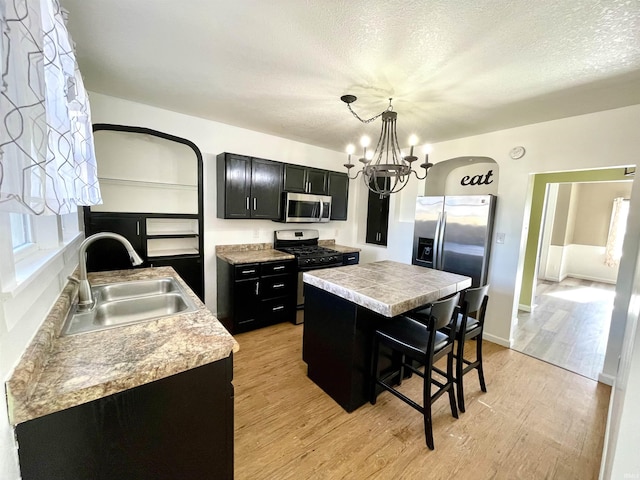 kitchen with a kitchen bar, sink, a center island, appliances with stainless steel finishes, and pendant lighting