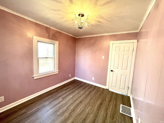 spare room featuring crown molding, an inviting chandelier, dark wood-type flooring, and a textured ceiling