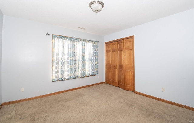 unfurnished bedroom featuring light carpet and a closet