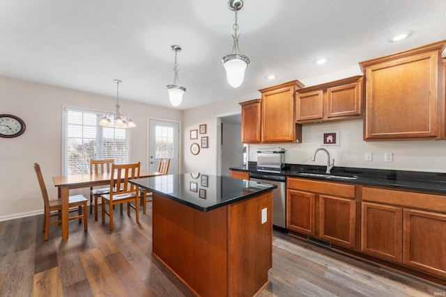 kitchen featuring dark hardwood / wood-style floors, pendant lighting, sink, a center island, and stainless steel dishwasher