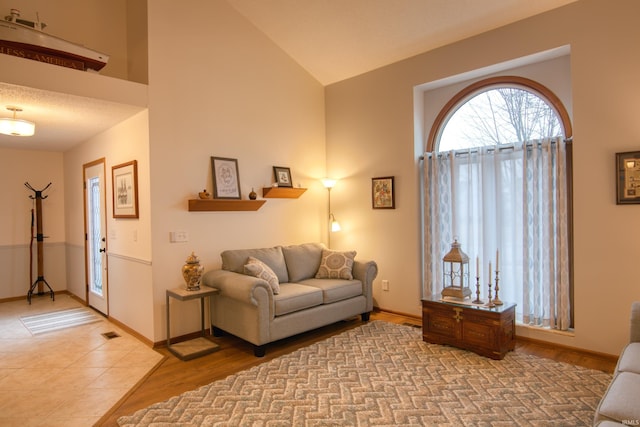 living room with high vaulted ceiling and light hardwood / wood-style flooring