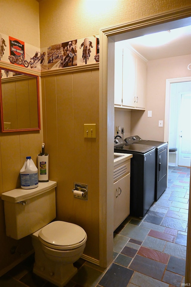 bathroom featuring washing machine and clothes dryer and toilet