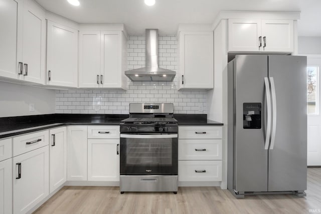 kitchen with white cabinetry, stainless steel appliances, light wood-type flooring, and wall chimney range hood