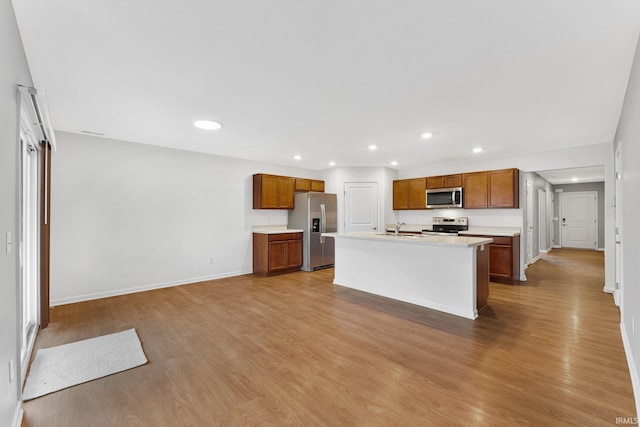 kitchen with sink, wood-type flooring, an island with sink, and appliances with stainless steel finishes