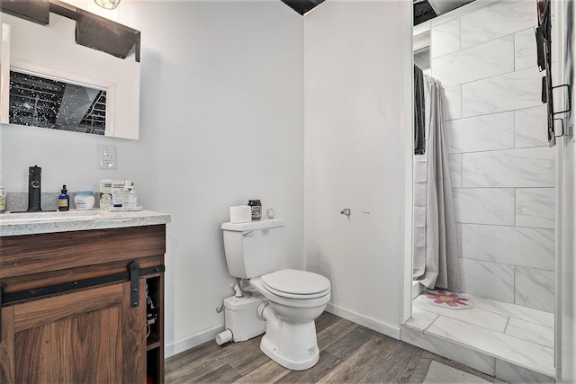 bathroom with vanity, hardwood / wood-style floors, toilet, and tiled shower