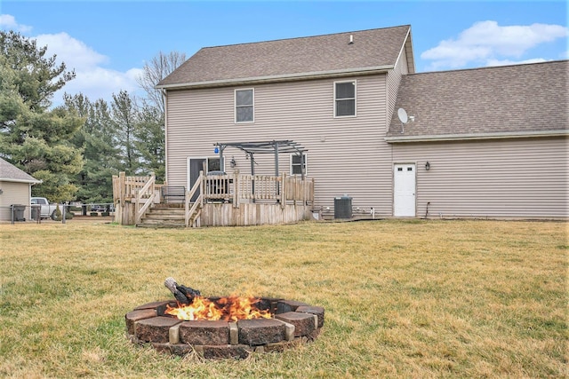 rear view of house with a lawn, a deck, a pergola, central AC, and an outdoor fire pit