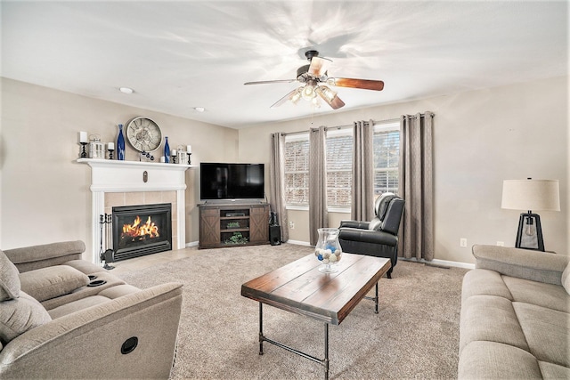 carpeted living room featuring ceiling fan and a tiled fireplace