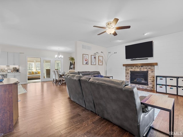 living room with ceiling fan with notable chandelier, a brick fireplace, and hardwood / wood-style floors