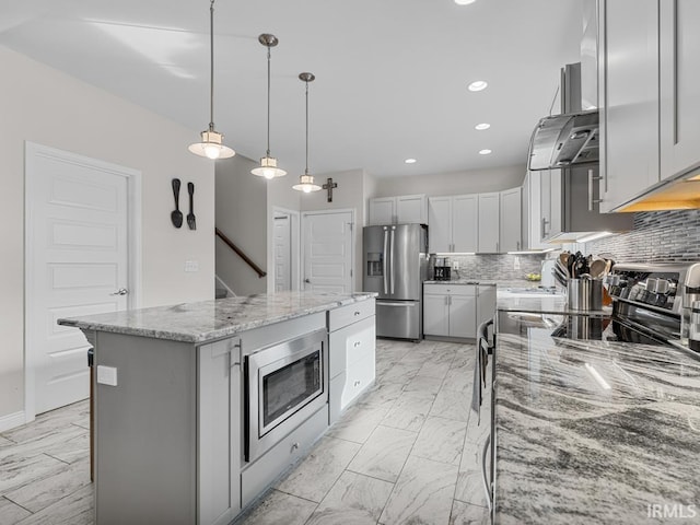 kitchen featuring appliances with stainless steel finishes, a kitchen island, light stone countertops, island exhaust hood, and decorative light fixtures