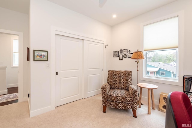 living area with plenty of natural light and light carpet