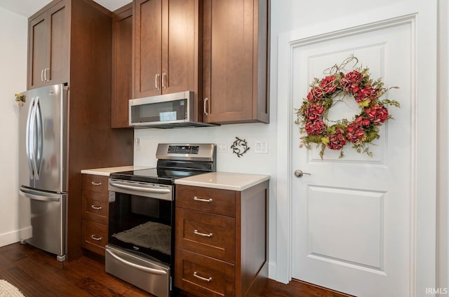 kitchen with appliances with stainless steel finishes and dark hardwood / wood-style floors