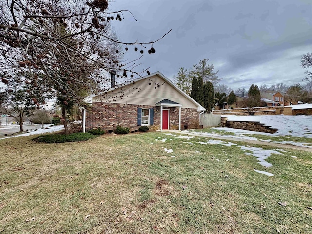 view of front of property with a front yard, brick siding, and fence