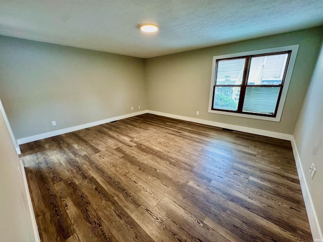 spare room with visible vents, a textured ceiling, baseboards, and dark wood-style flooring