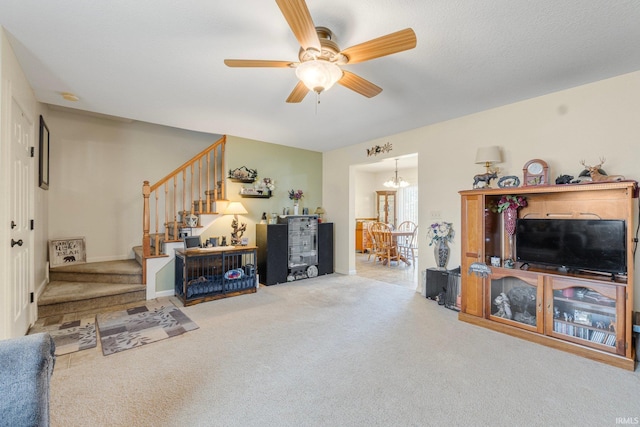 carpeted living room featuring ceiling fan with notable chandelier