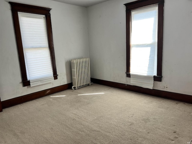 carpeted spare room featuring radiator heating unit and a wealth of natural light