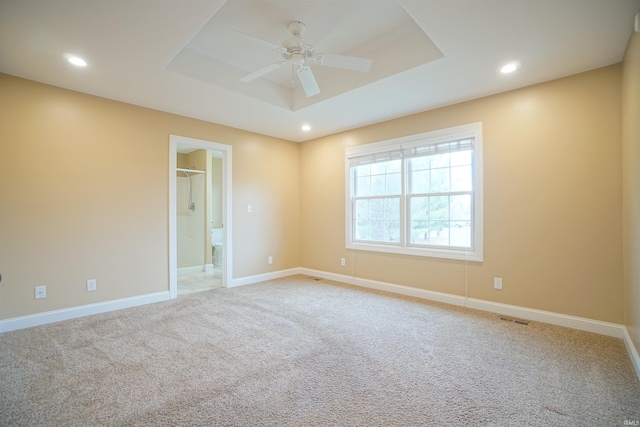 carpeted spare room featuring ceiling fan and a tray ceiling