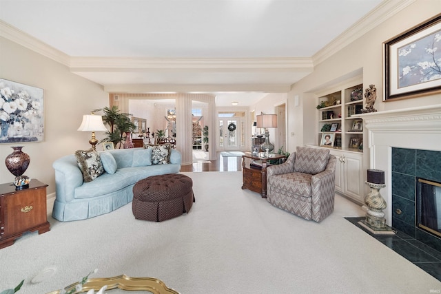 carpeted living room featuring crown molding, a fireplace, and built in shelves