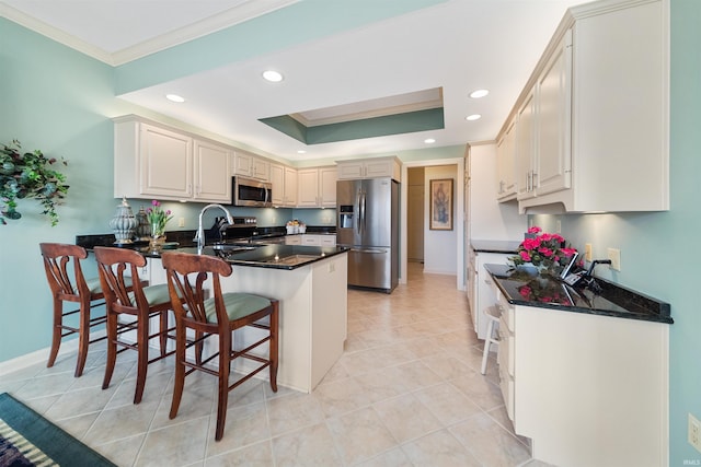 kitchen with crown molding, stainless steel appliances, a tray ceiling, a kitchen bar, and kitchen peninsula