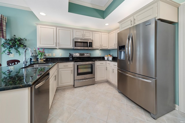 kitchen with sink, appliances with stainless steel finishes, white cabinetry, light tile patterned flooring, and dark stone counters