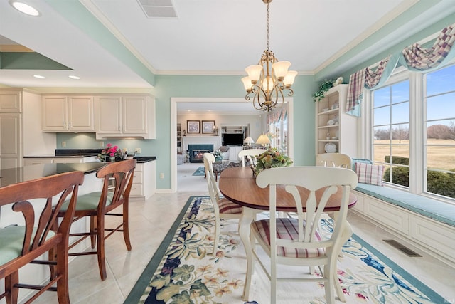 dining area featuring crown molding, light tile patterned flooring, and an inviting chandelier