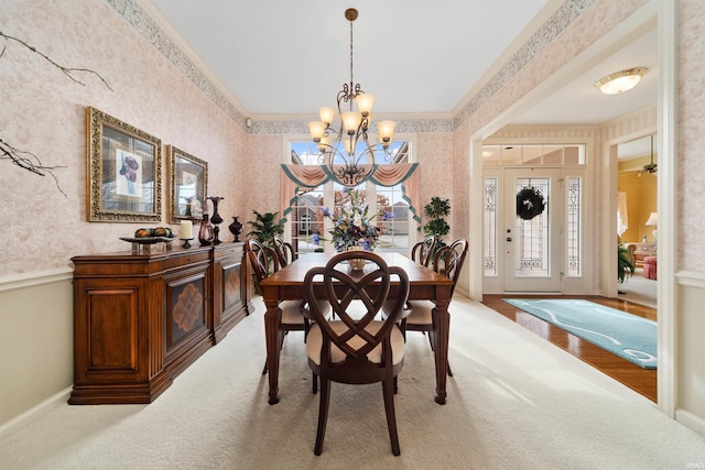 carpeted dining space with crown molding and a chandelier