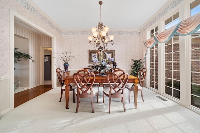 dining room with ornamental molding, carpet flooring, and an inviting chandelier