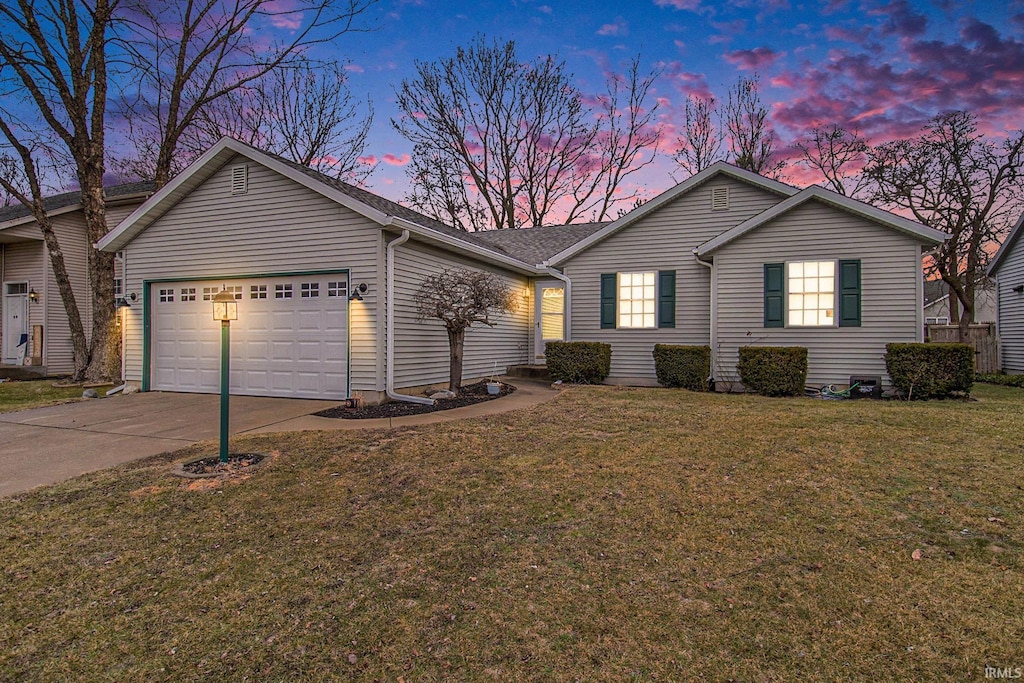 ranch-style house with a garage and a lawn