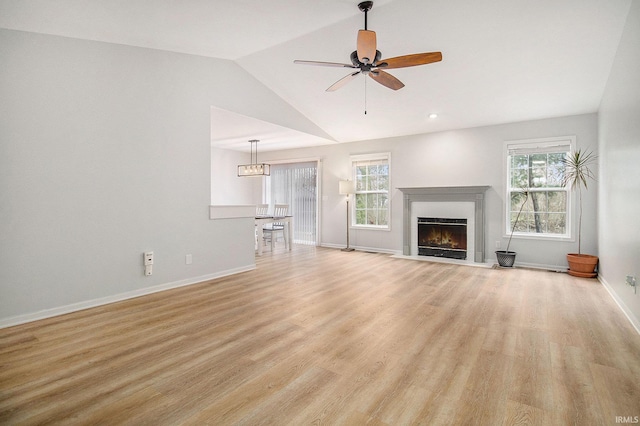 unfurnished living room featuring vaulted ceiling, ceiling fan, light hardwood / wood-style floors, and a wealth of natural light