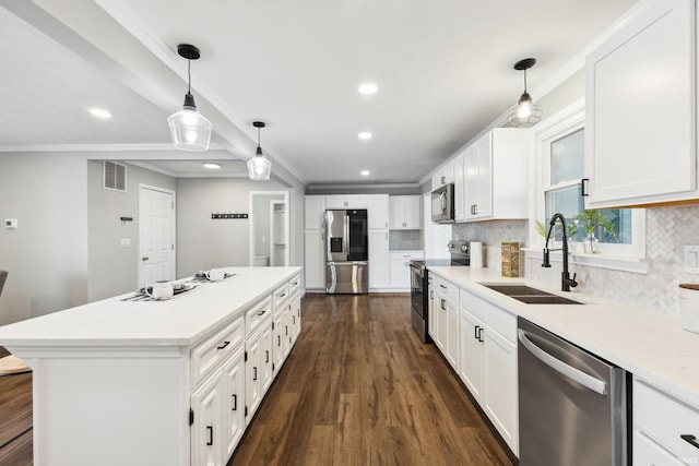 kitchen with sink, appliances with stainless steel finishes, hanging light fixtures, a center island, and white cabinets