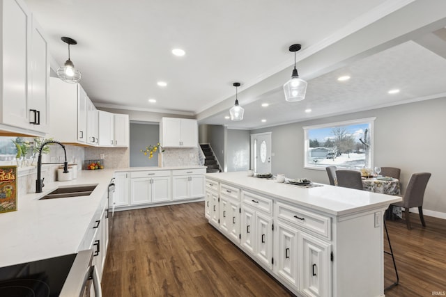 kitchen featuring a kitchen island, sink, white cabinets, and decorative light fixtures