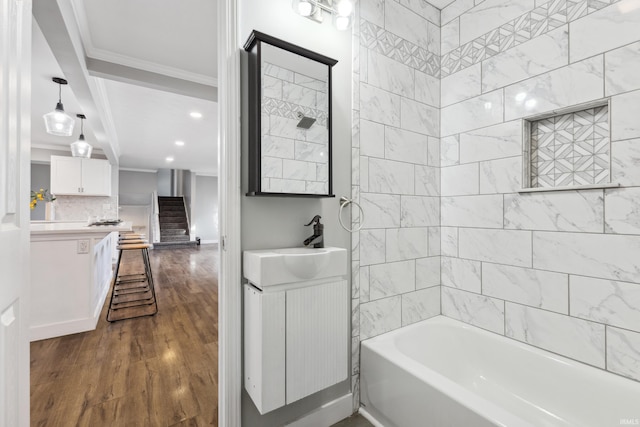 bathroom featuring crown molding, wood-type flooring, vanity, shower / washtub combination, and backsplash