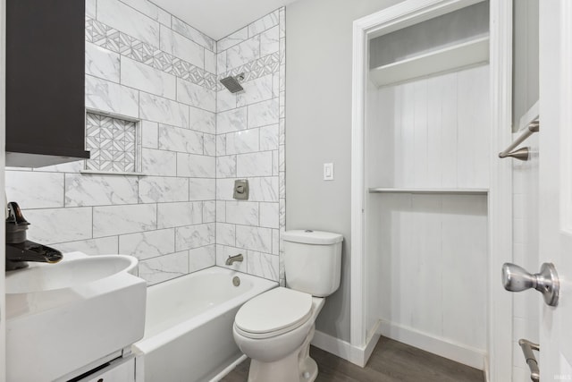 full bathroom with hardwood / wood-style flooring, tiled shower / bath, toilet, and sink