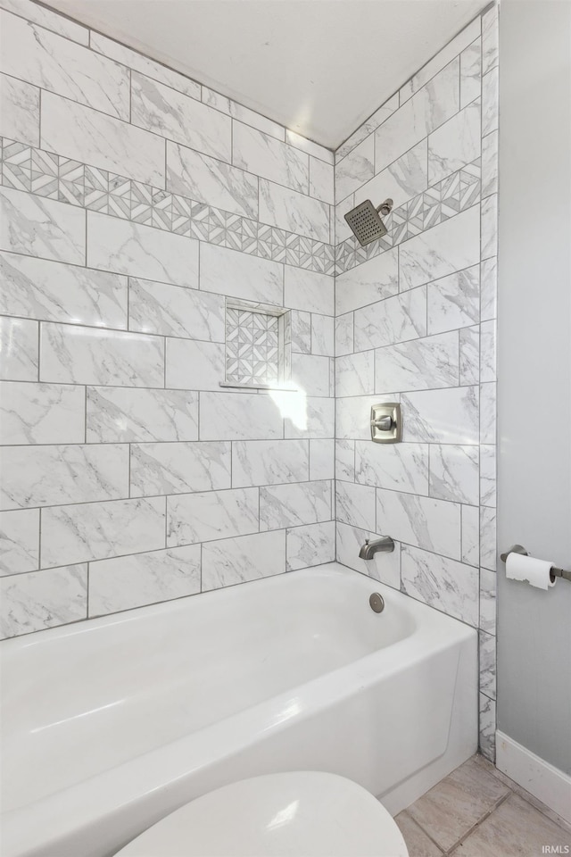 bathroom featuring toilet and tiled shower / bath