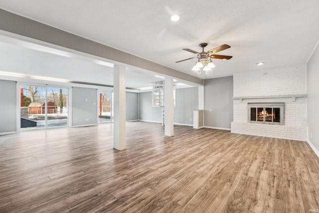 unfurnished living room featuring hardwood / wood-style flooring, a fireplace, and ceiling fan