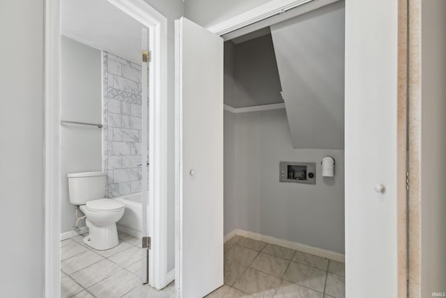 bathroom with tiled shower / bath combo, tile patterned floors, and toilet