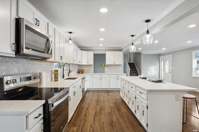 kitchen featuring a kitchen bar, sink, white cabinetry, appliances with stainless steel finishes, and a kitchen island