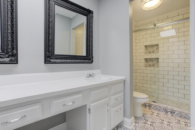 bathroom featuring vanity, tile patterned floors, toilet, and a tile shower