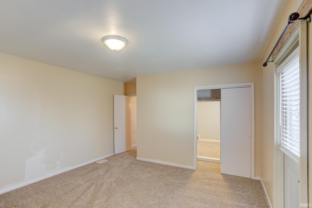 unfurnished bedroom with light colored carpet and a closet