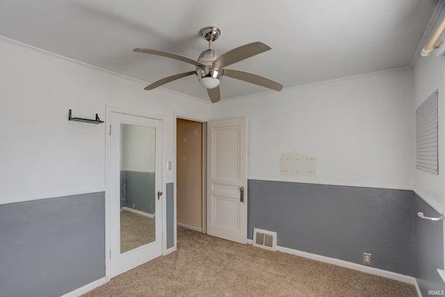 empty room featuring ceiling fan, light colored carpet, and ornamental molding