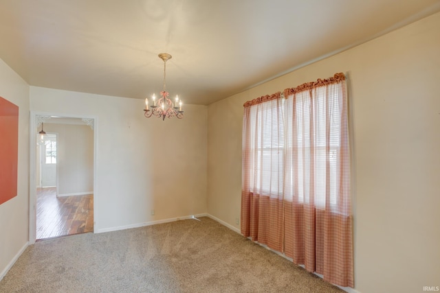 carpeted spare room with a chandelier