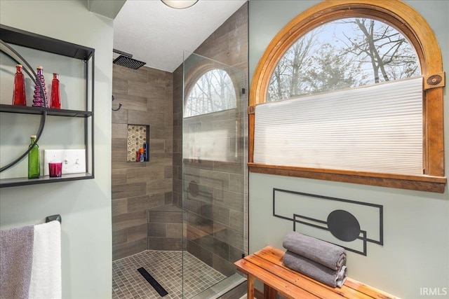 bathroom with a textured ceiling and a tile shower