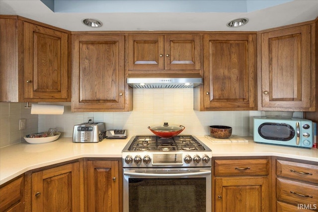 kitchen with stainless steel gas stove, backsplash, and ventilation hood