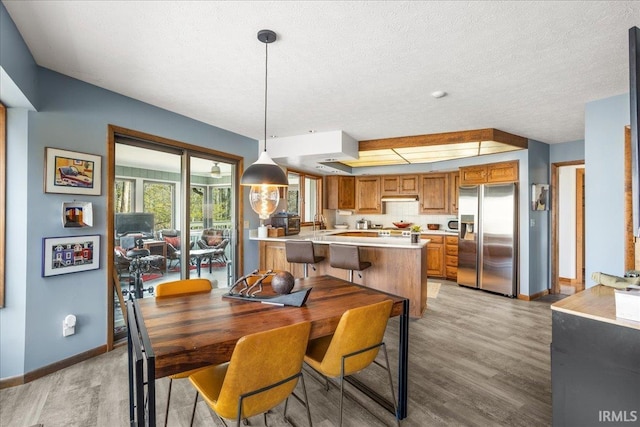 dining room featuring sink, a textured ceiling, and light wood-type flooring