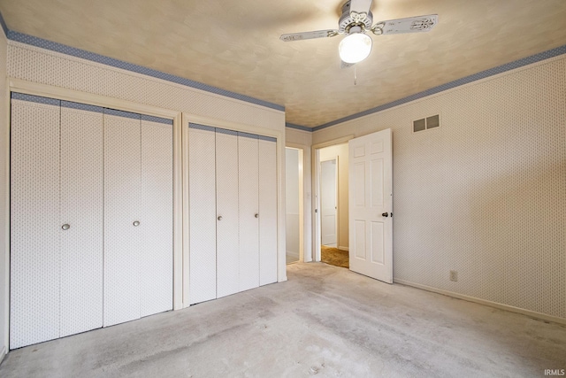 unfurnished bedroom with light carpet, ceiling fan, and multiple closets