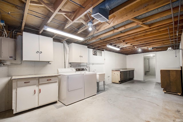 washroom featuring independent washer and dryer, sink, electric panel, and cabinets