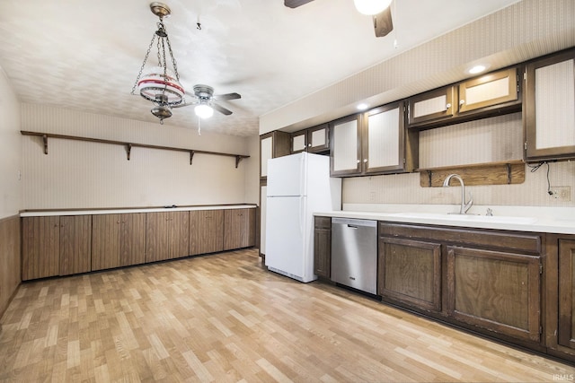 kitchen with dishwasher, sink, white refrigerator, hanging light fixtures, and light wood-type flooring