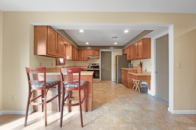 kitchen featuring stainless steel appliances, a kitchen bar, and kitchen peninsula